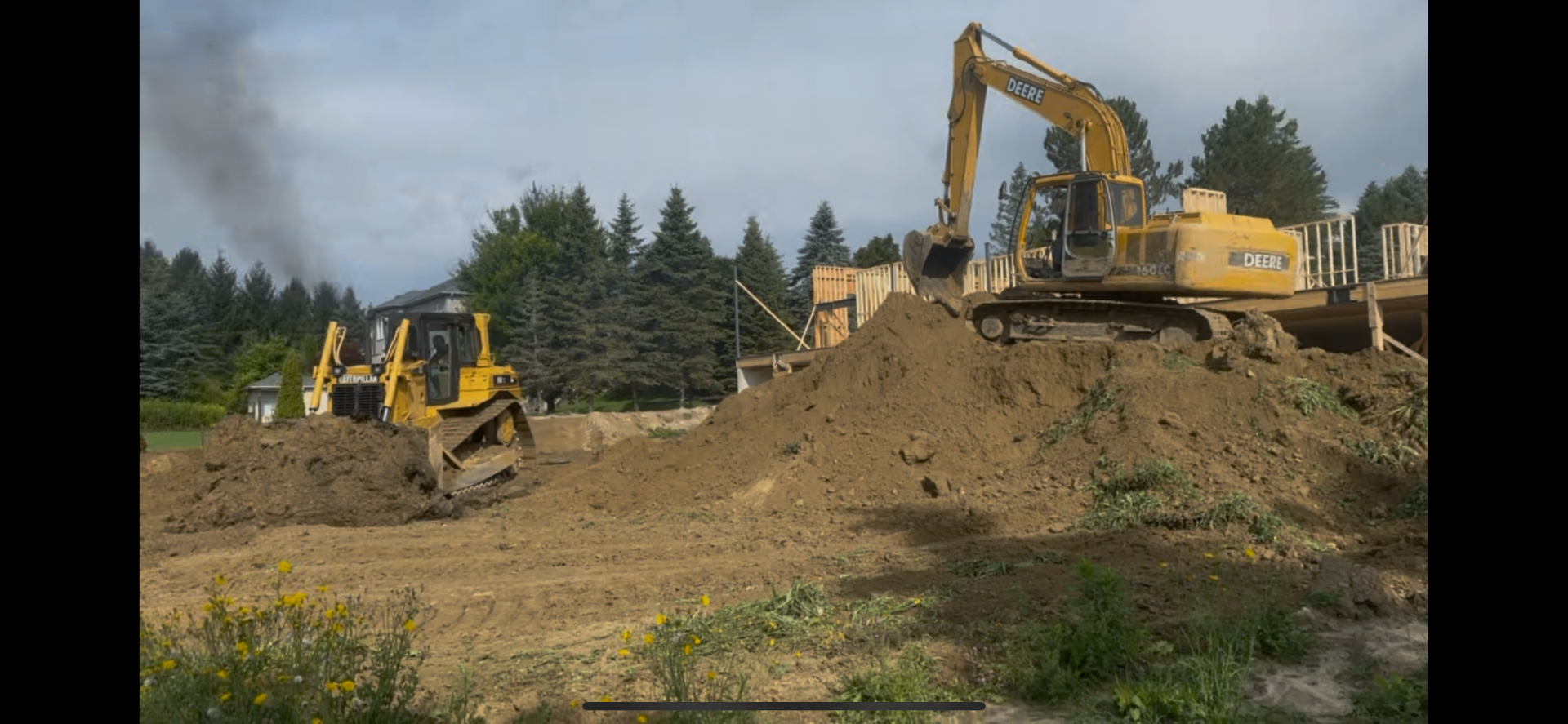 Deere excavator and Cat dozer shaping a residential build site